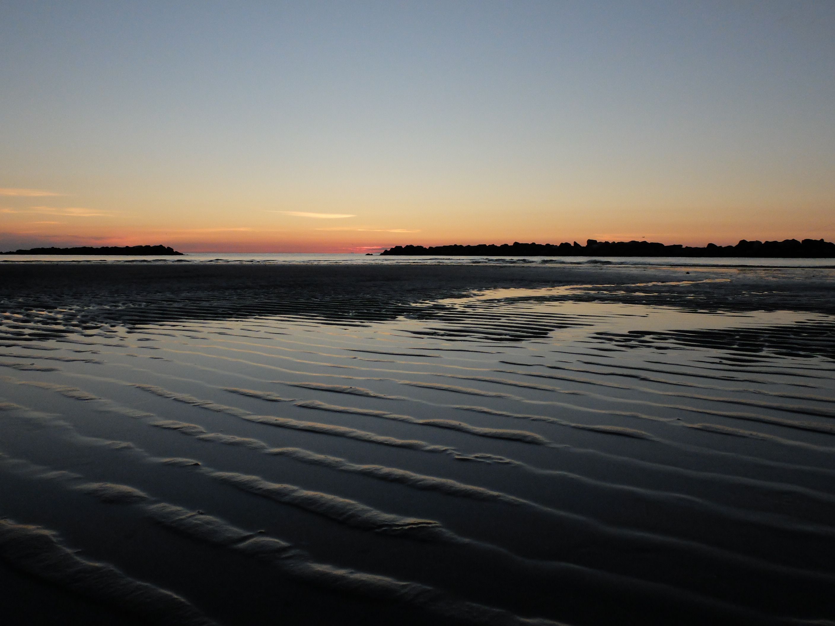 Rippled wet sand and a calm Gulf horizon at dusk